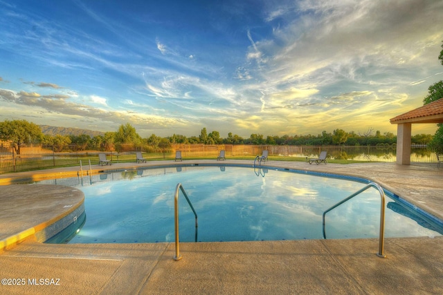 pool at dusk with fence and a fenced in pool