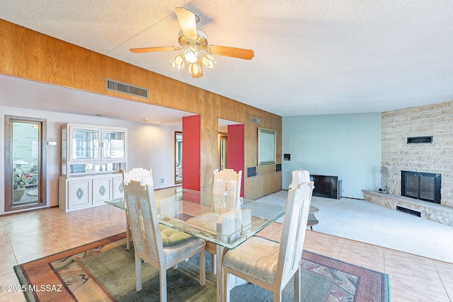 32551 S Moyza Ranch Rd, Amado, AZ 85645 - dining room featuring light tile patterned flooring, wooden walls, ceiling fan, visible vents, and a fireplace