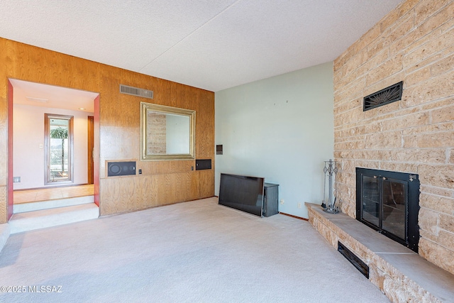 32551 S Moyza Ranch Rd, Amado, AZ 85645 - living area featuring carpet, a textured ceiling, wooden walls, visible vents, and a fireplace