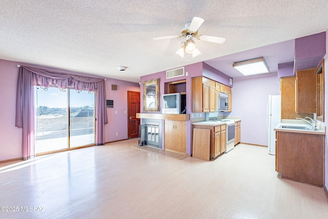 32551 S Moyza Ranch Rd, Amado, AZ 85645 - kitchen featuring light countertops, white appliances, a sink, visible vents, and brown cabinetry