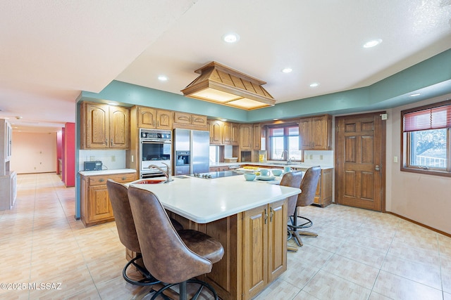 32551 S Moyza Ranch Rd, Amado, AZ 85645 - kitchen with light countertops, double wall oven, a kitchen breakfast bar, a large island, and stainless steel refrigerator with ice dispenser