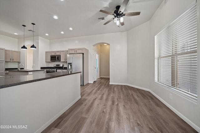 kitchen with stainless steel appliances, dark countertops, arched walkways, visible vents, and a ceiling fan