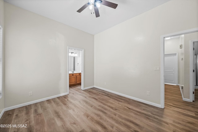 unfurnished bedroom featuring baseboards, light wood-style floors, ensuite bath, and a ceiling fan