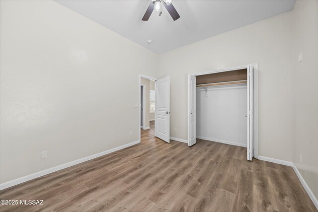 unfurnished bedroom with baseboards, ceiling fan, wood finished floors, and a closet