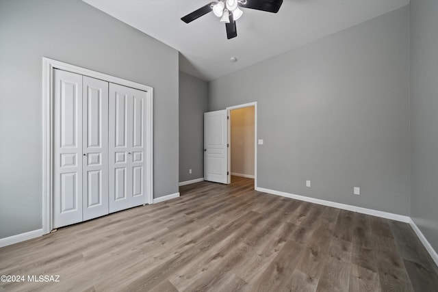 unfurnished bedroom featuring a closet, baseboards, ceiling fan, wood finished floors, and lofted ceiling