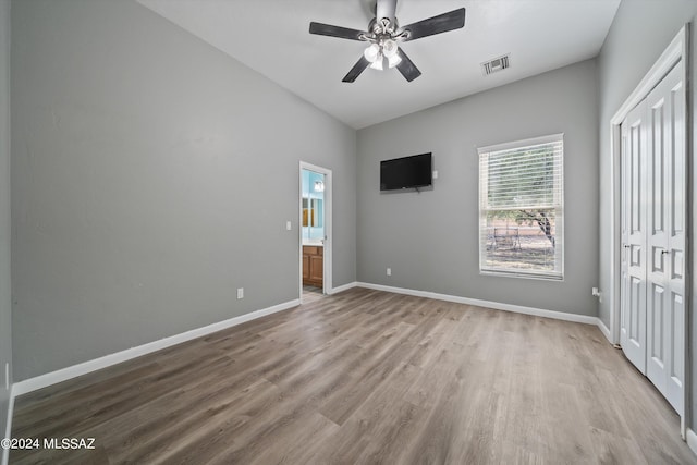 unfurnished bedroom featuring a closet, visible vents, baseboards, wood finished floors, and ensuite bath