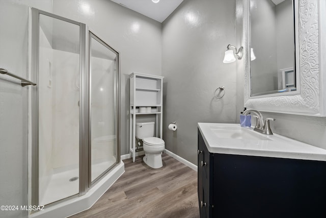full bath featuring toilet, vanity, a shower stall, wood finished floors, and baseboards