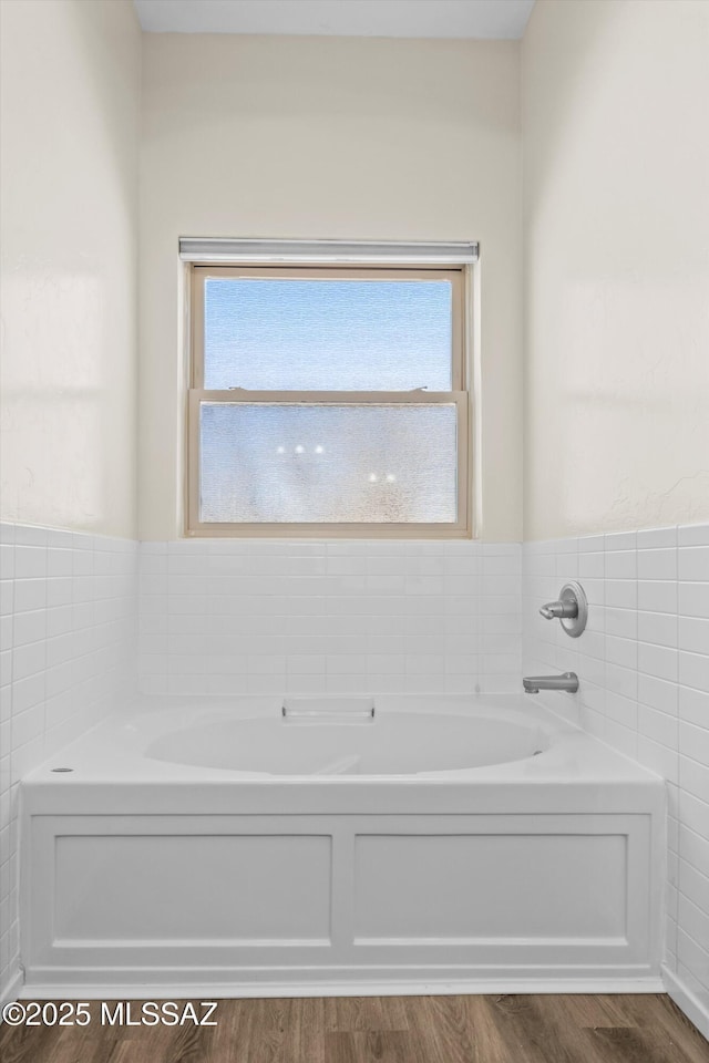 full bathroom with wood finished floors, a garden tub, and a wealth of natural light