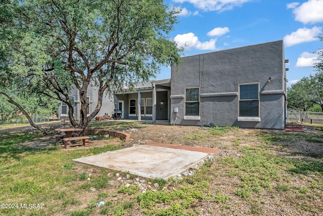 back of property featuring a yard, stucco siding, and fence