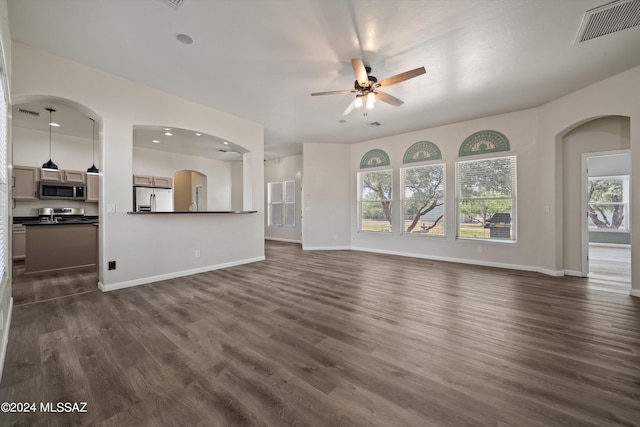 unfurnished living room featuring a ceiling fan, dark wood-style floors, baseboards, and visible vents