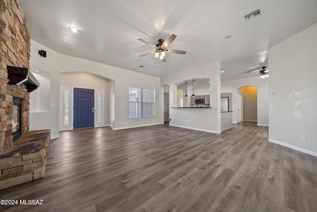unfurnished living room with a ceiling fan, dark wood-style floors, a fireplace, and visible vents
