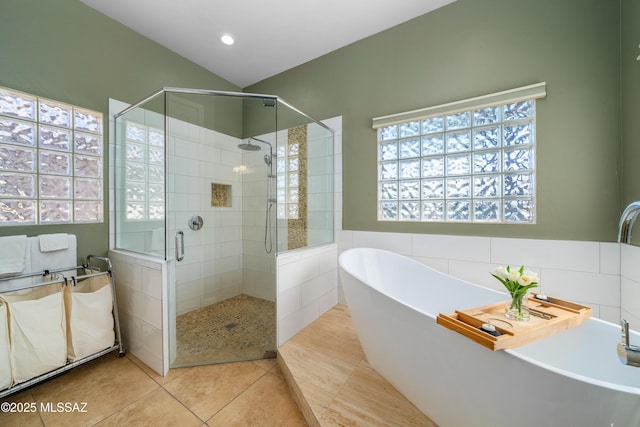 bathroom featuring tile walls, a stall shower, a freestanding tub, and tile patterned floors