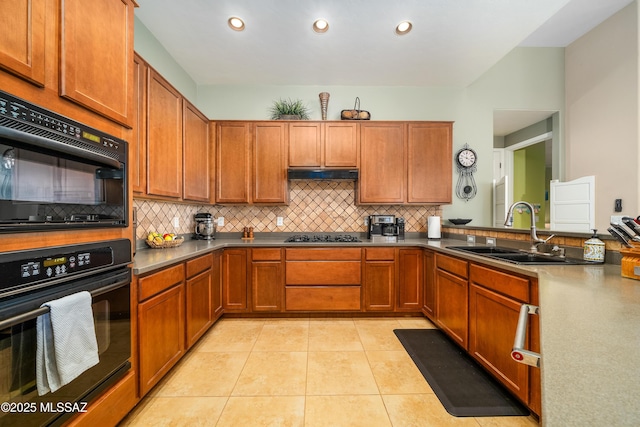 kitchen featuring black appliances, under cabinet range hood, light tile patterned flooring, a sink, and brown cabinets