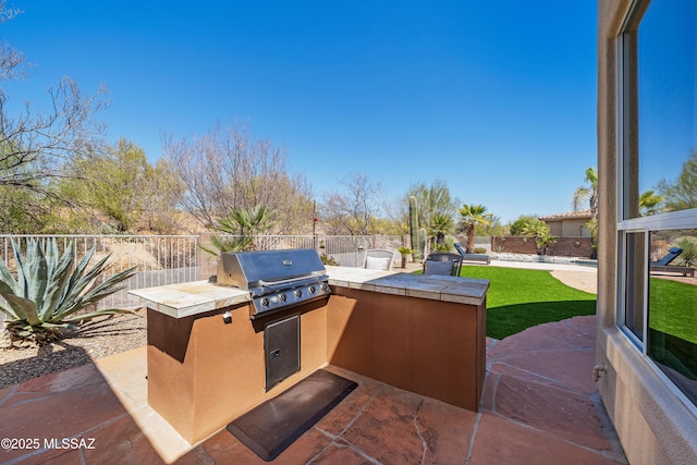 view of patio / terrace featuring a grill, an outdoor kitchen, and a fenced backyard