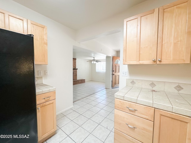 3926 E Camino De Palmas, Tucson, AZ 85711 - kitchen with light brown cabinetry, freestanding refrigerator, tile countertops, ceiling fan, and light tile patterned flooring