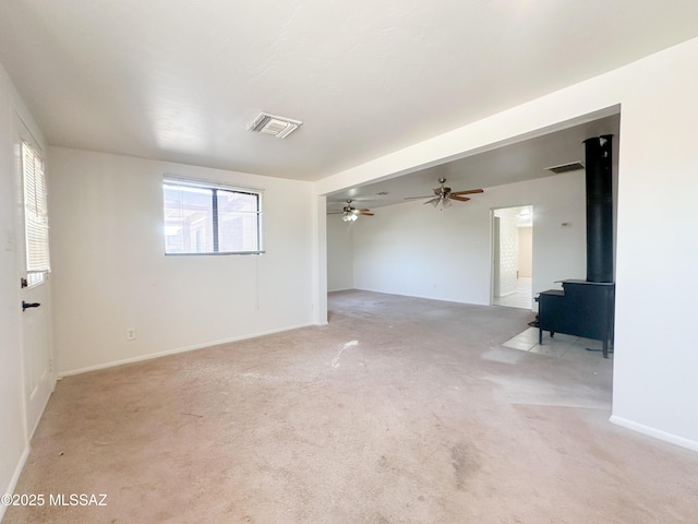 3926 E Camino De Palmas, Tucson, AZ 85711 - empty room featuring a wood stove, light colored carpet, a ceiling fan, and baseboards