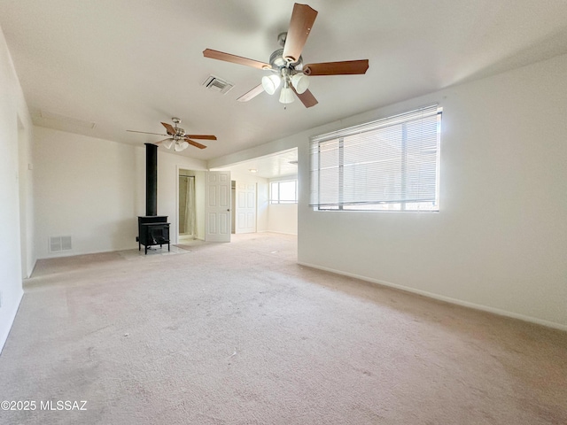3926 E Camino De Palmas, Tucson, AZ 85711 - unfurnished room featuring a wood stove, a ceiling fan, and light carpet