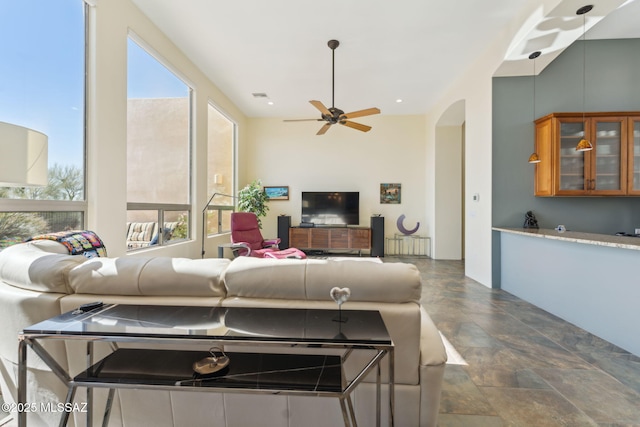 living room featuring a ceiling fan, radiator, arched walkways, and visible vents