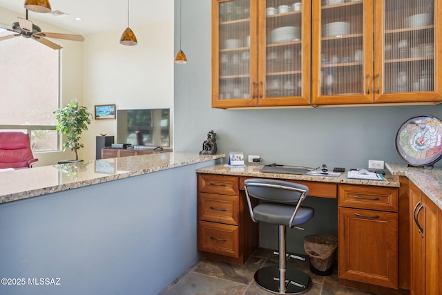 home office with stone finish floor and a ceiling fan
