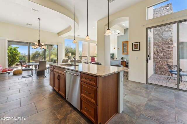 kitchen featuring dishwasher, a sink, light stone counters, hanging light fixtures, and brown cabinetry