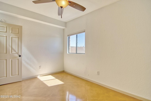empty room featuring baseboards, a ceiling fan, and light tile patterned flooring