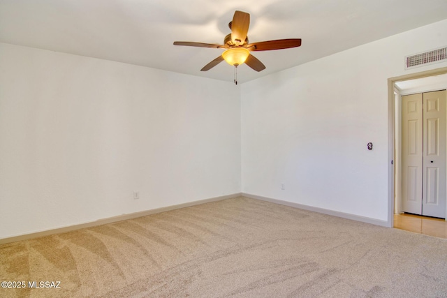 spare room with baseboards, visible vents, a ceiling fan, and light colored carpet