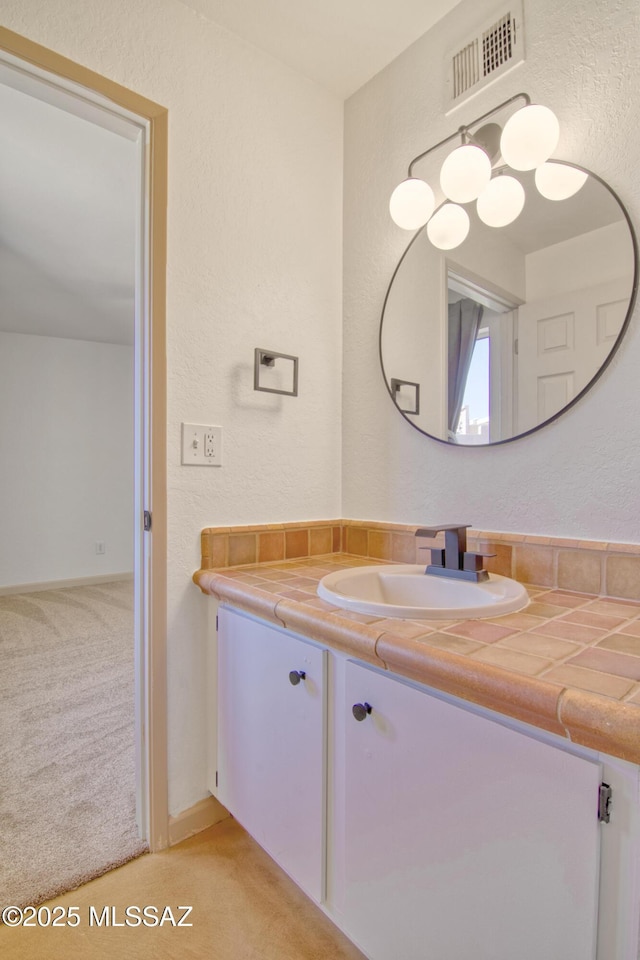bathroom featuring a textured wall, visible vents, and vanity