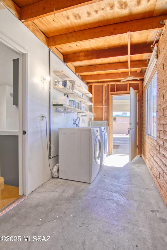 clothes washing area with washing machine and clothes dryer, wooden ceiling, brick wall, and laundry area