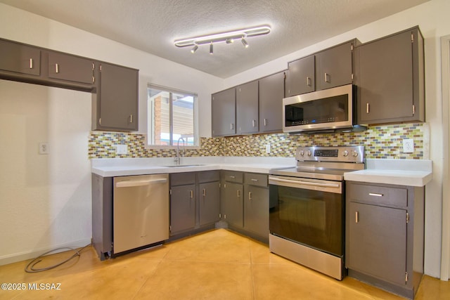 kitchen featuring light countertops, tasteful backsplash, stainless steel appliances, and a sink
