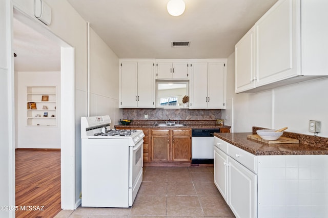 kitchen featuring a sink, white cabinetry, visible vents, white appliances, and dark countertops