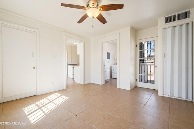unfurnished bedroom featuring light tile patterned floors, washer / clothes dryer, connected bathroom, visible vents, and electric panel