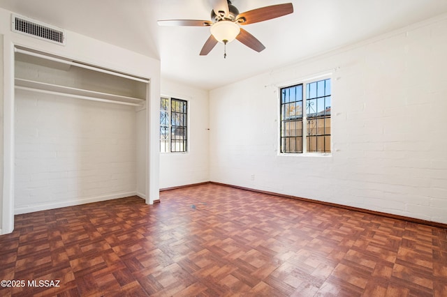 unfurnished bedroom with visible vents, multiple windows, and brick wall