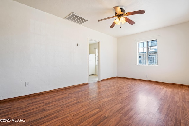 empty room featuring baseboards, visible vents, a ceiling fan, and wood finished floors