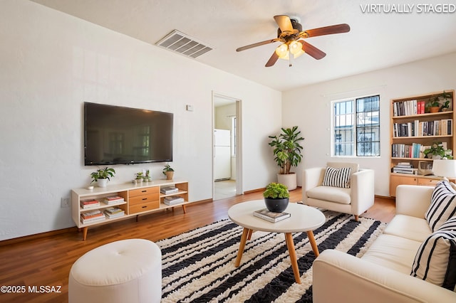 living room featuring baseboards, ceiling fan, visible vents, and light wood-type flooring