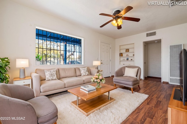 living room featuring baseboards, dark wood-style floors, visible vents, a ceiling fan, and built in features