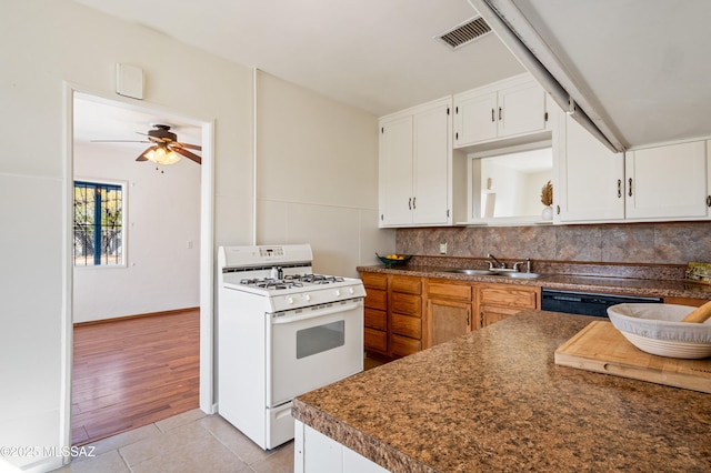 kitchen featuring backsplash, gas range gas stove, a sink, and visible vents
