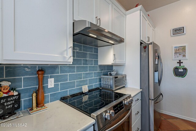 3437 S Abrego Dr, Green Valley, AZ 85614 - kitchen featuring white cabinetry, tasteful backsplash, under cabinet range hood, stainless steel appliances, and baseboards