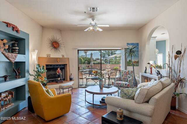 3437 S Abrego Dr, Green Valley, AZ 85614 - living room with a fireplace, visible vents, arched walkways, and a ceiling fan