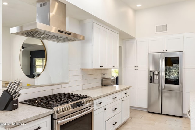 kitchen with visible vents, a wealth of natural light, wall chimney exhaust hood, and appliances with stainless steel finishes