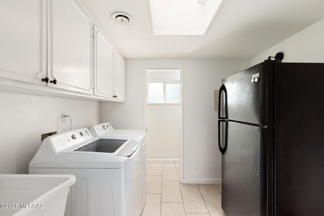 laundry area with a skylight, separate washer and dryer, light tile patterned floors, a sink, and baseboards