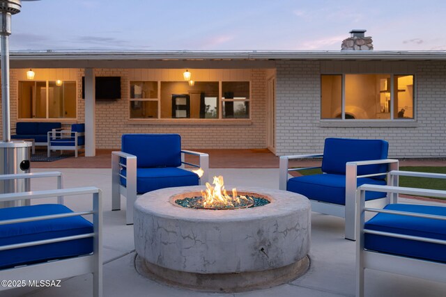 patio terrace at dusk with an outdoor living space with a fire pit