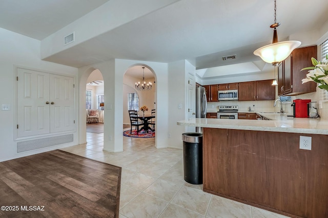 kitchen featuring a sink, light countertops, arched walkways, stainless steel appliances, and visible vents