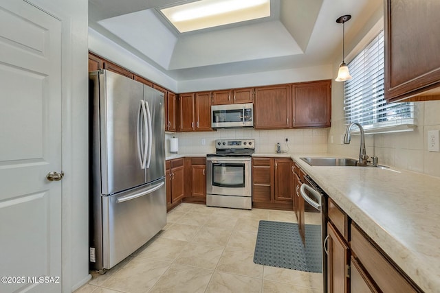 kitchen featuring backsplash, appliances with stainless steel finishes, a sink, light tile patterned floors, and a raised ceiling