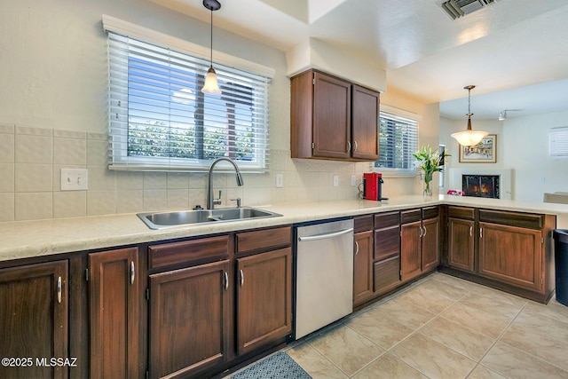kitchen featuring decorative backsplash, a lit fireplace, visible vents, dishwasher, and a sink