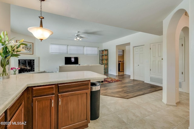 kitchen featuring a ceiling fan, decorative light fixtures, arched walkways, light countertops, and open floor plan