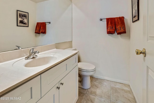 bathroom with vanity, baseboards, tile patterned flooring, and toilet