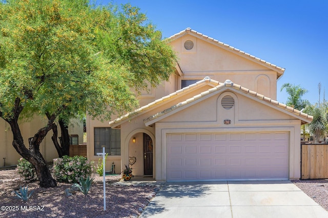 mediterranean / spanish house featuring fence, an attached garage, a tile roof, stucco siding, and concrete driveway