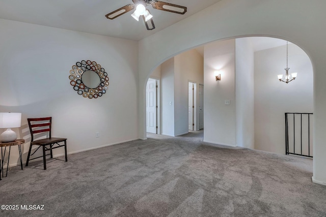 spare room featuring baseboards, arched walkways, carpet, and ceiling fan with notable chandelier