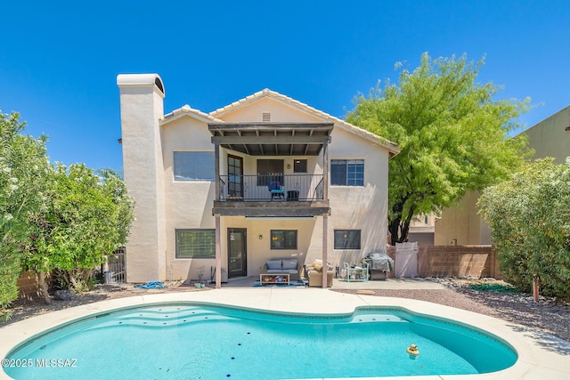back of property with a balcony, a fenced backyard, an outdoor pool, stucco siding, and a patio area