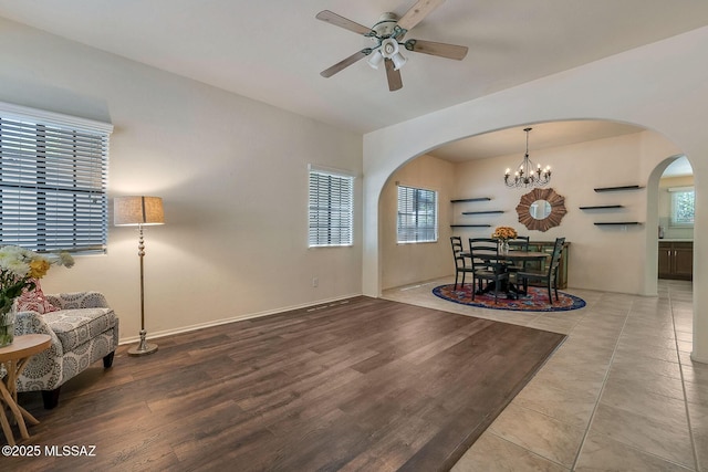 dining area with arched walkways, plenty of natural light, wood finished floors, and ceiling fan with notable chandelier